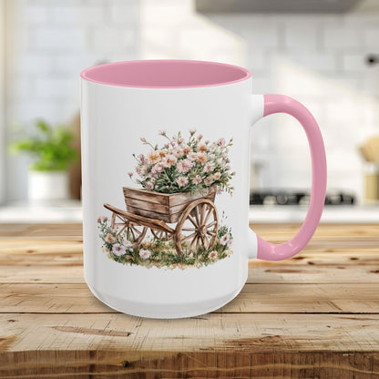 15oz white ceramic mug with pink interior/handle, featuring a watercolor wheelbarrow overflowing with pink blooms.