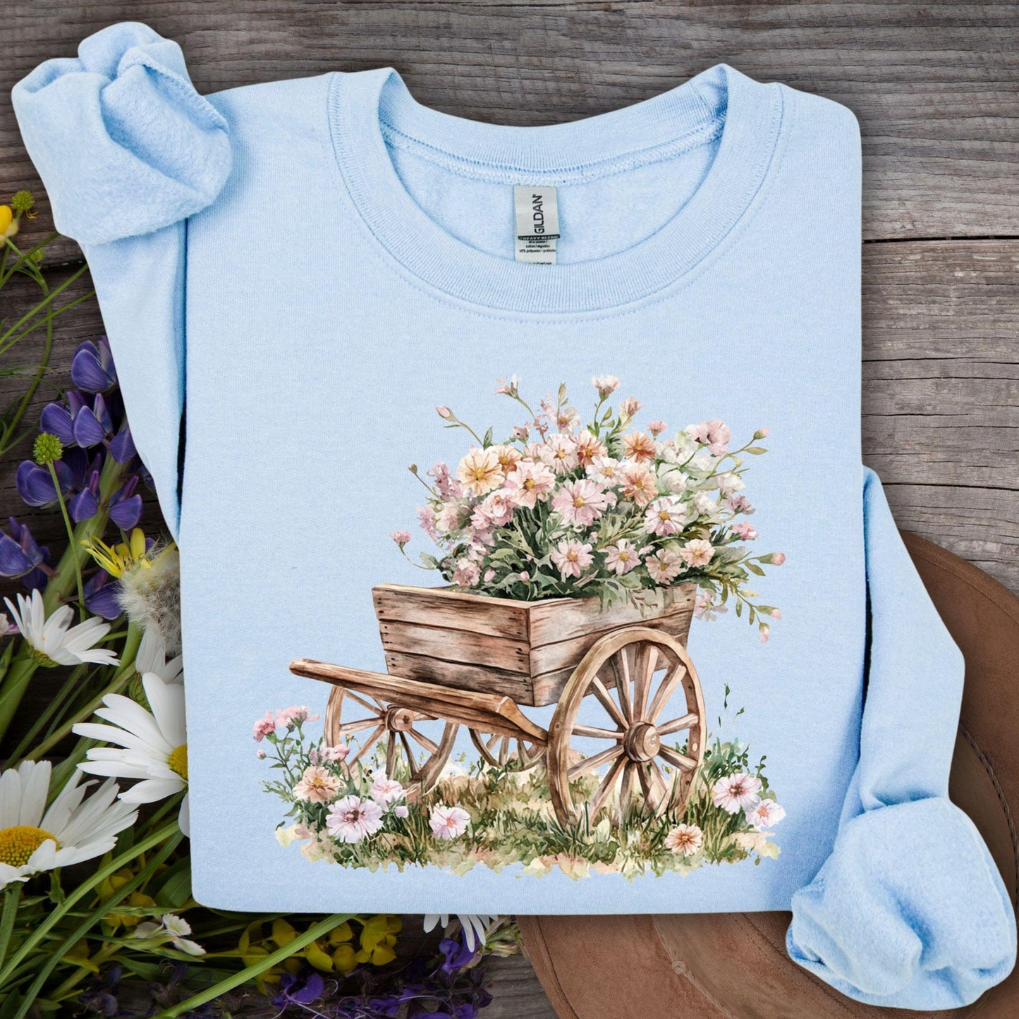 Light blue sweatshirt with a watercolor graphic of a rustic wooden wagon overflowing with pink carnations.