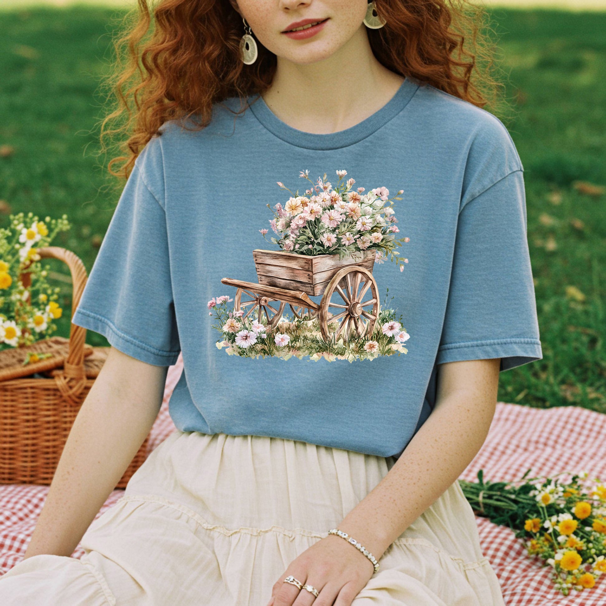 Garment-dyed blue t-shirt with a vintage botanical illustration of a rustic wooden wagon overflowing with flowers.