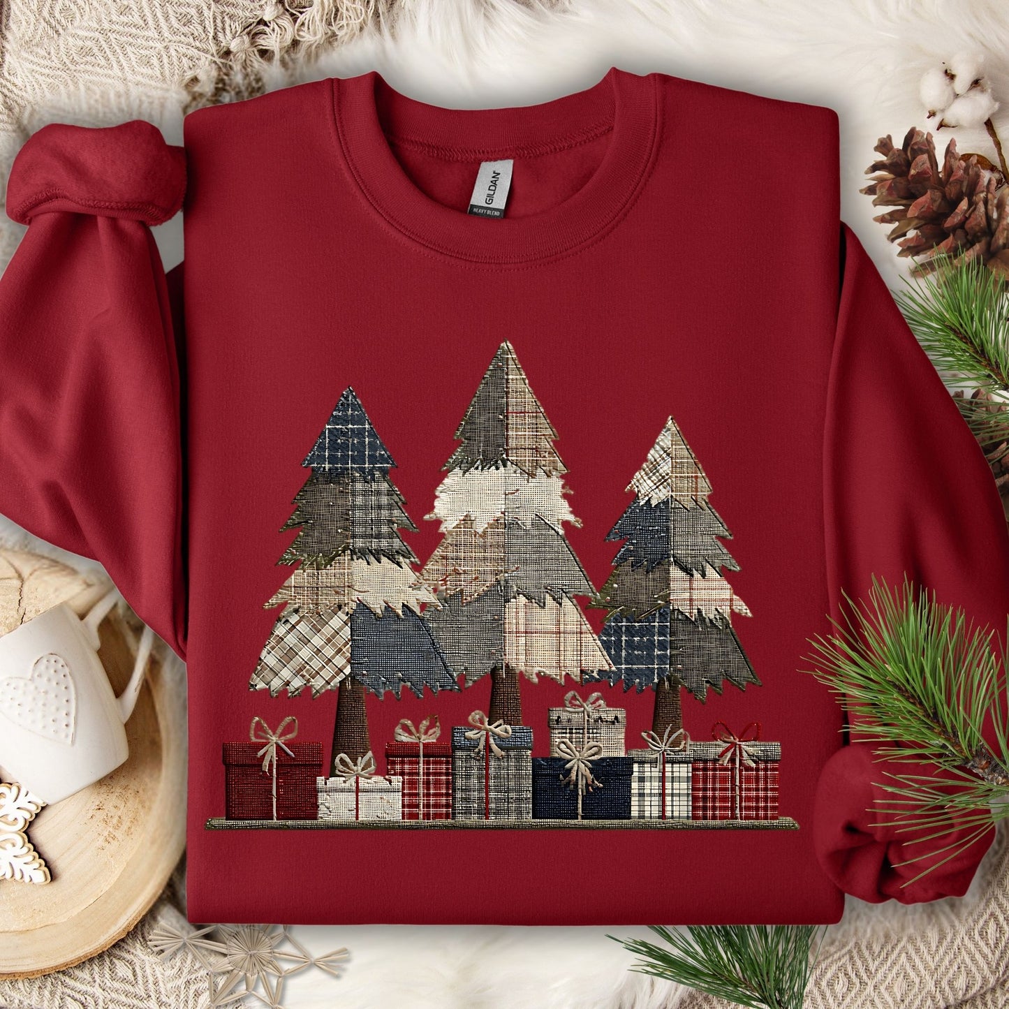 Cardinal Red Gildan sweatshirt with faux patchwork Christmas trees and gifts, on a cozy white blanket.