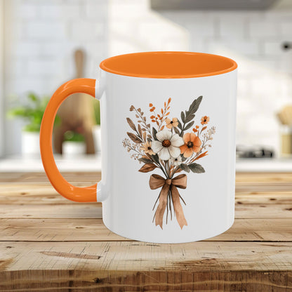White ceramic mug with orange handle and interior, featuring a sepia and cream floral bouquet design.