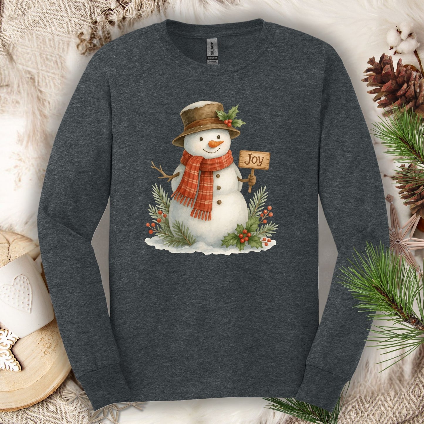 Dark Heather long sleeve tee with a watercolor snowman holding a "Joy" sign, holly, and snowy branches.