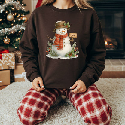 Brown Gildan 18000 sweatshirt with a watercolor snowman holding a "Joy" sign, surrounded by holly.