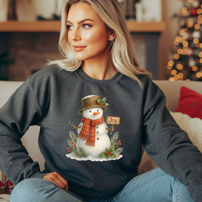 Woman wearing a charcoal gray sweatshirt with a watercolor snowman holding a "Joy" sign.