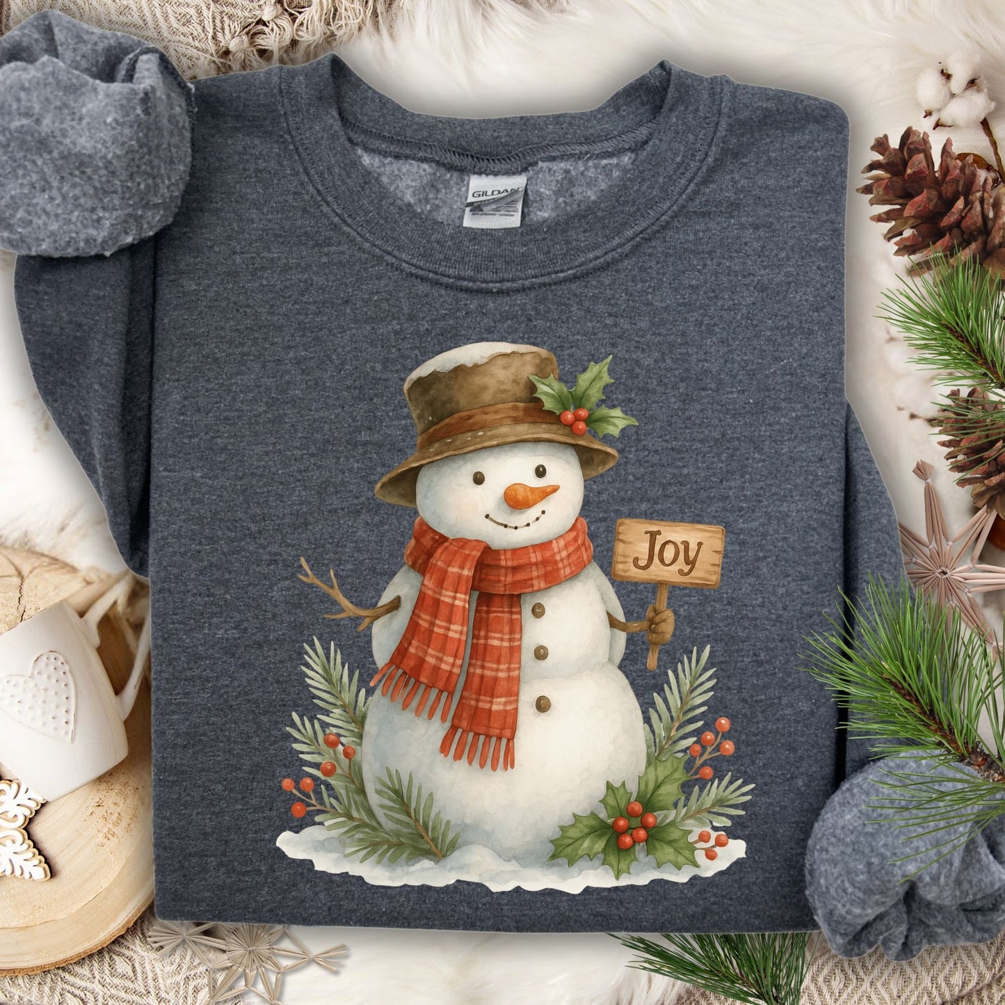 Dark Heather Gildan 18000 sweatshirt with a watercolor snowman holding a "Joy" sign, surrounded by holly.