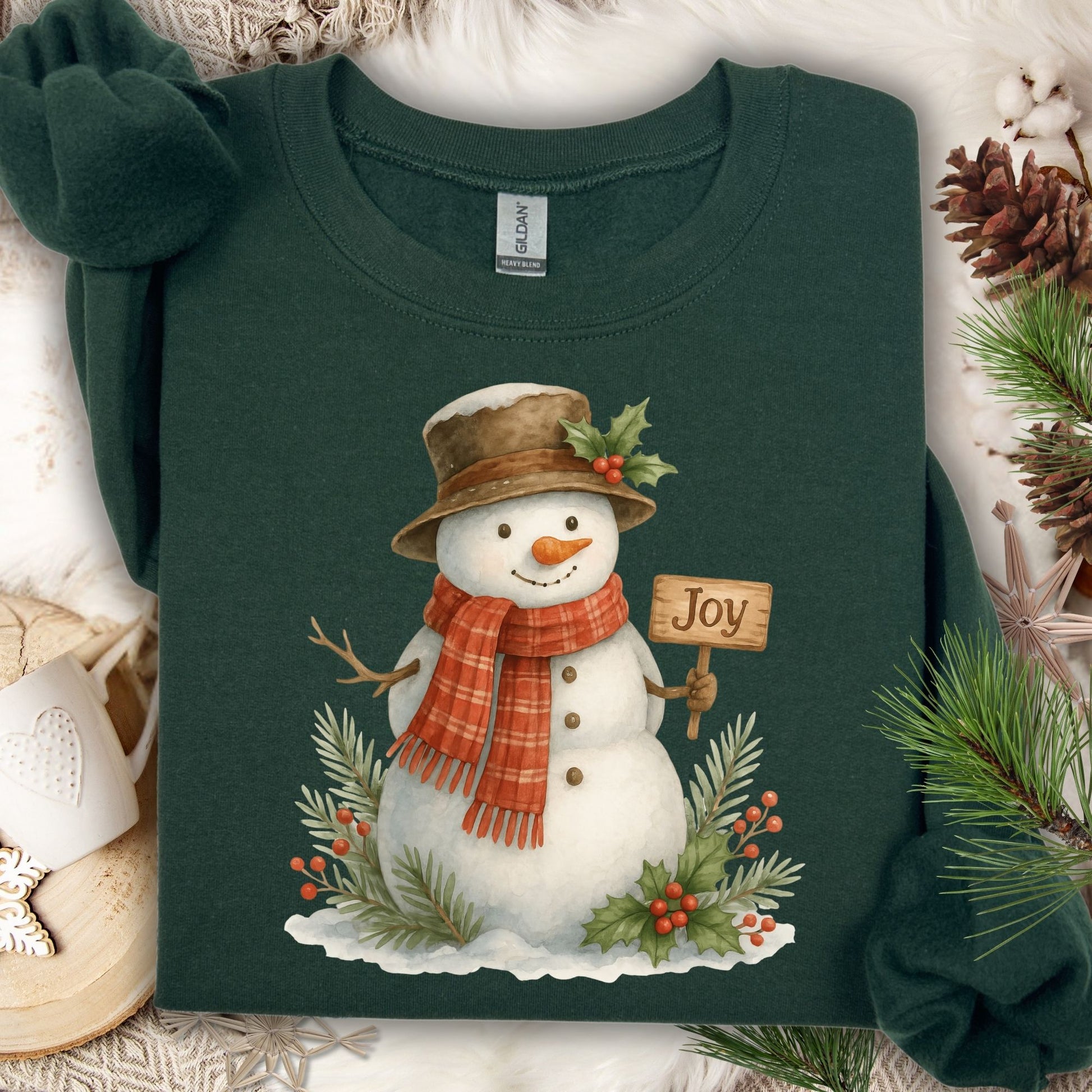 Forest Green Gildan 18000 sweatshirt with a watercolor snowman holding a "Joy" sign, surrounded by holly.