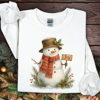 White Gildan 18000 sweatshirt with a watercolor snowman holding a "Joy" sign, surrounded by holly.