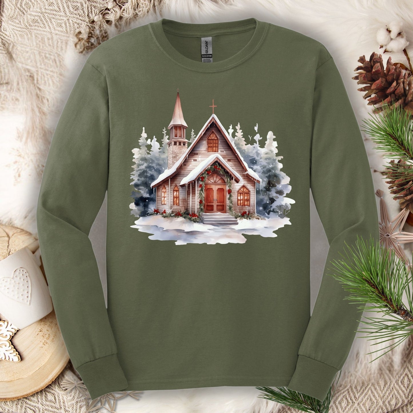 Military Green long sleeve tee with a rustic chapel, evergreens, snow, holly, and pine garland design.