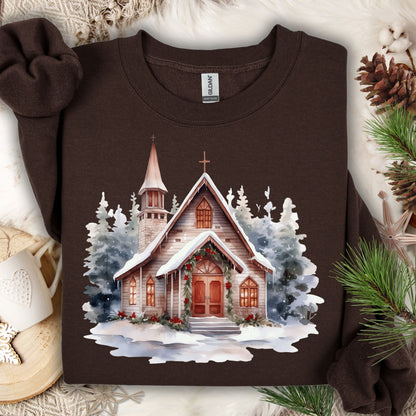 Dark Chocolate Gildan sweatshirt with a watercolor rustic chapel in snow, festive greenery, and evergreens.