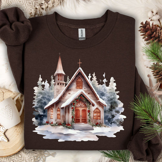 Dark Chocolate Gildan sweatshirt with a watercolor rustic chapel in snow, festive greenery, and evergreens.