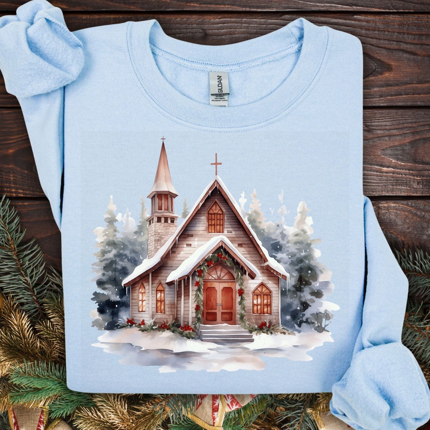 Light blue Gildan sweatshirt, size S, with a watercolor rustic chapel in snow and Christmas greenery.