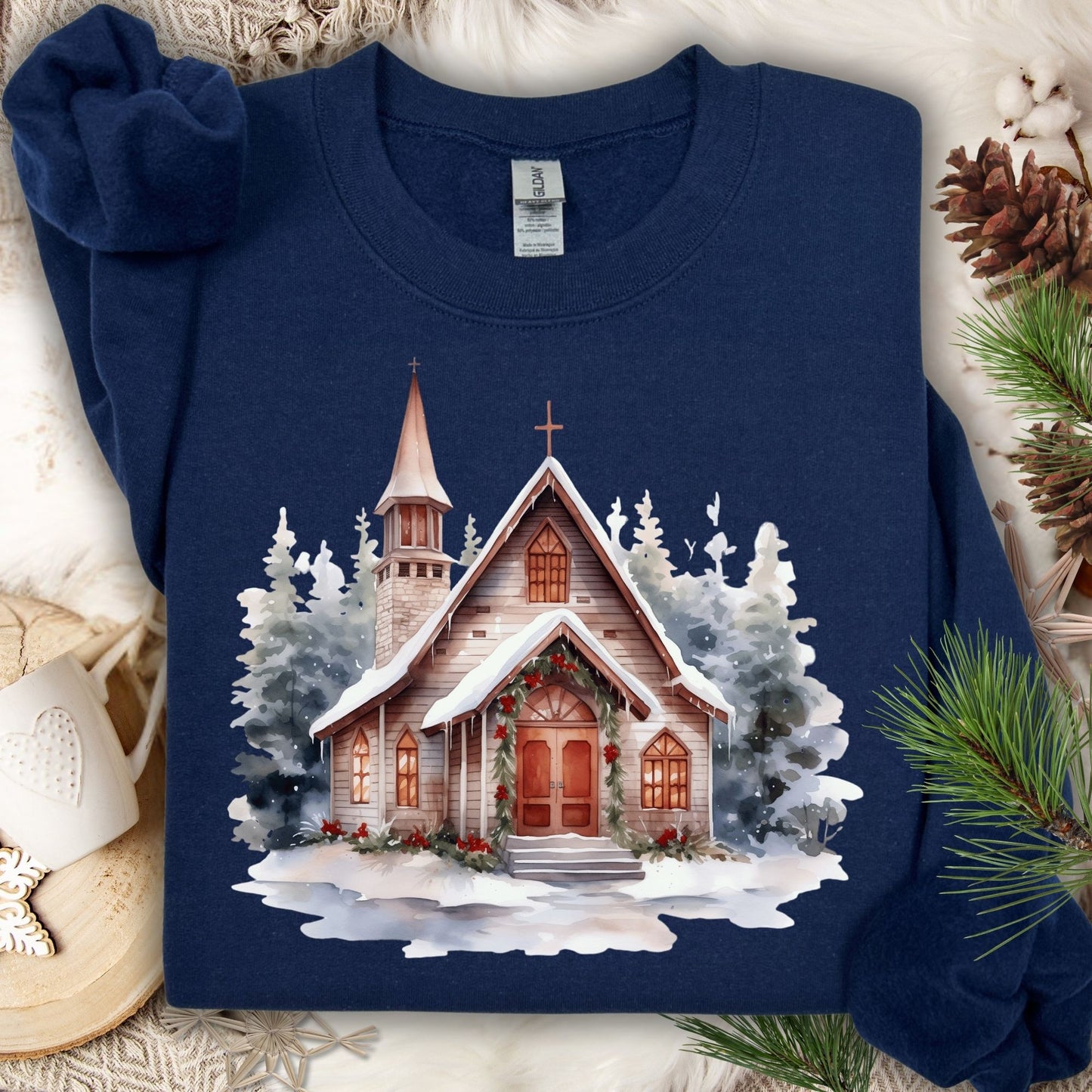 Navy Gildan sweatshirt with a watercolor rustic chapel in snow, adorned with Christmas greenery.