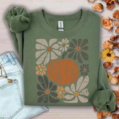 Military green sweatshirt with a rustic pumpkin and floral design, styled with jeans and fall leaves.