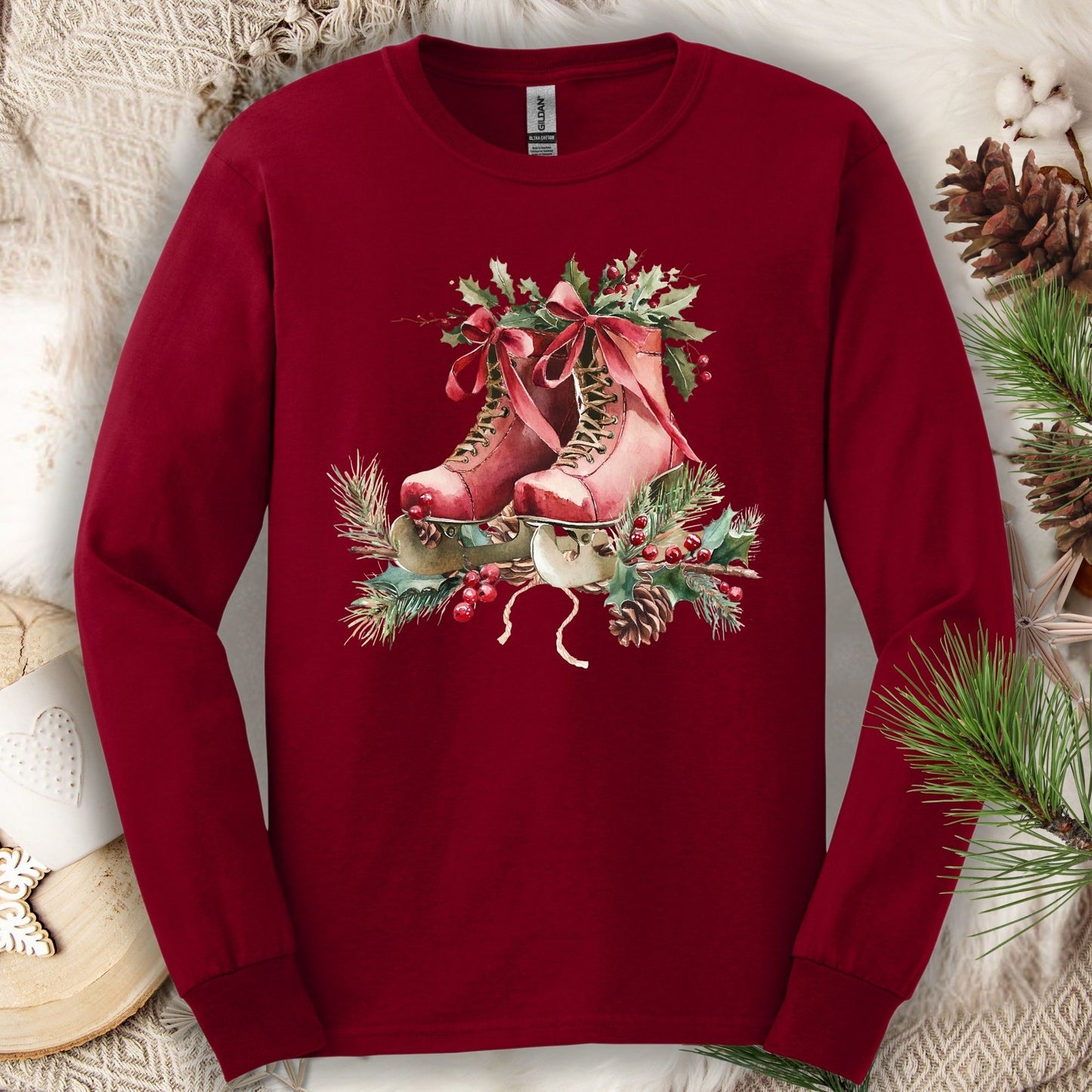 Cardinal Red long sleeve tee with a watercolor design of rustic red ice skates, holly, and evergreens.