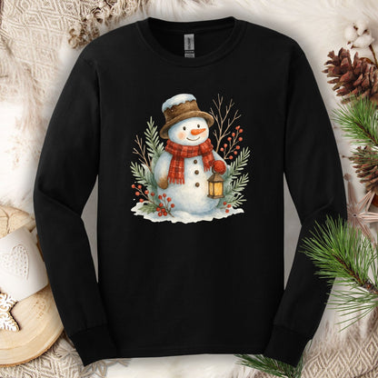 Black Gildan 2400 long sleeve tee with a watercolor snowman holding a lantern, surrounded by snowy branches.