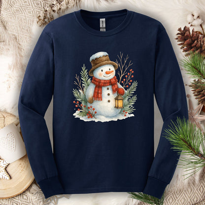Navy long sleeve cotton tee with a watercolor snowman holding a lantern, surrounded by snowy branches.