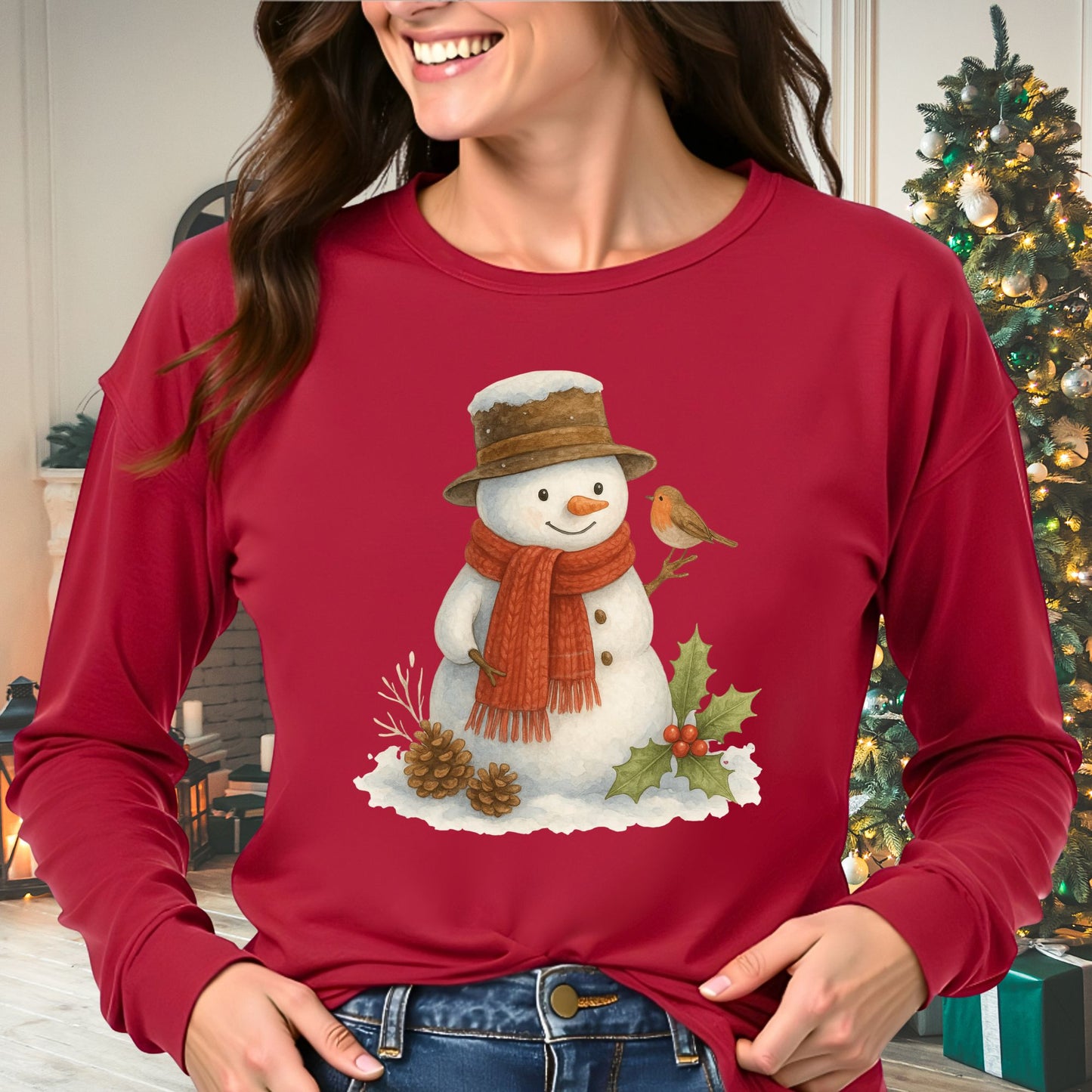 Red long-sleeve tee with a rustic watercolor snowman, holly, pinecones, and a sparrow.