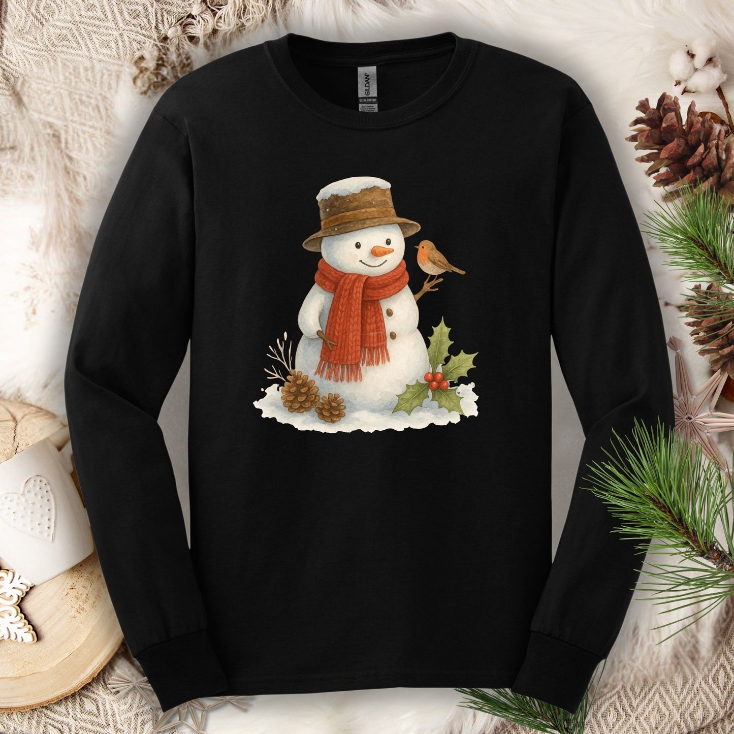 Black Gildan long sleeve tee with a rustic watercolor snowman holding a sparrow, holly, and pinecones.