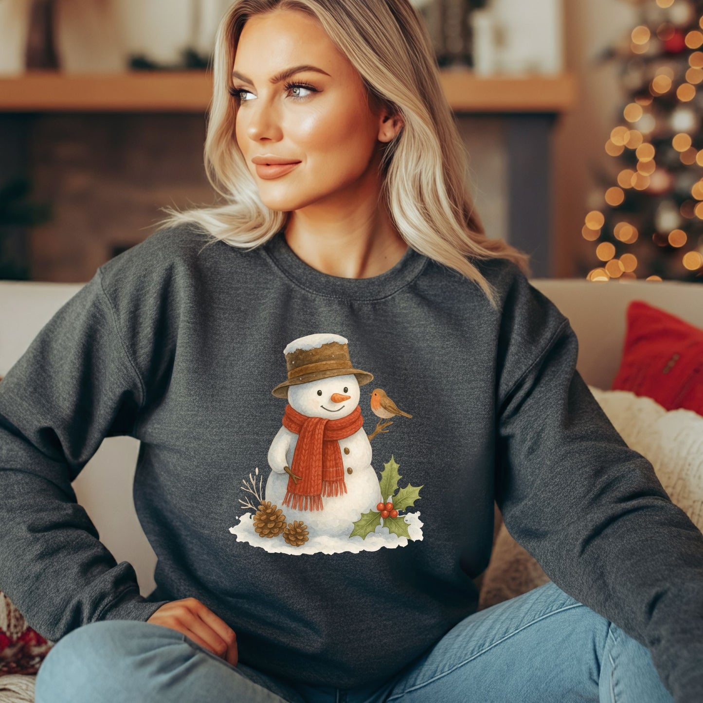 Woman in a dark gray Gildan 18000 sweatshirt with a watercolor snowman, holly, and sparrow design.