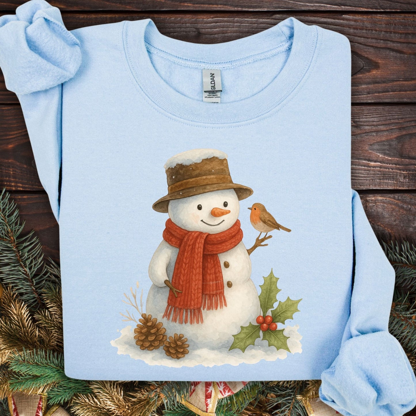 Light blue Gildan 18000 sweatshirt with a watercolor snowman, sparrow, holly, and pinecones.