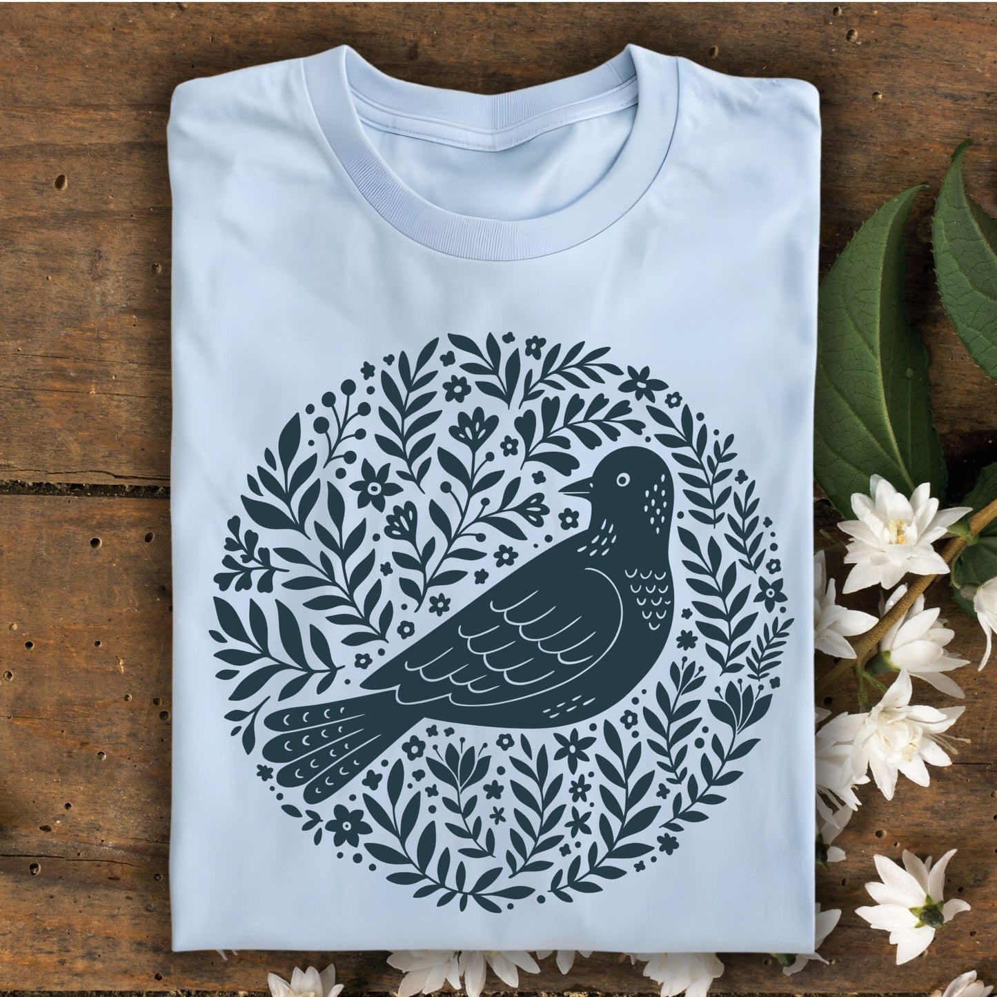 Light blue Scandinavian bird art T-shirt, size S, featuring a dark teal bird in a floral wreath design.