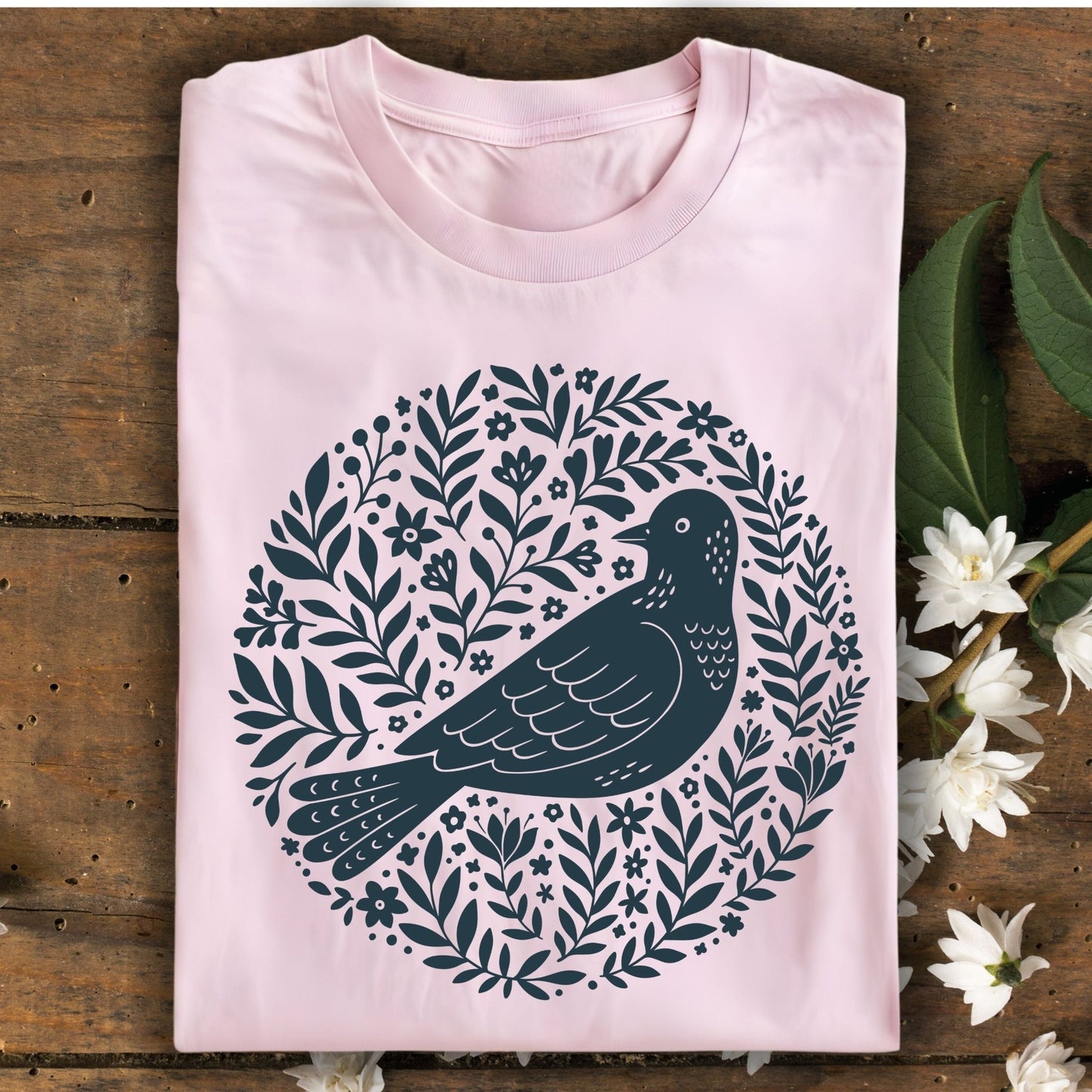 Light pink S-size t-shirt with a dark blue Scandinavian bird and floral design.