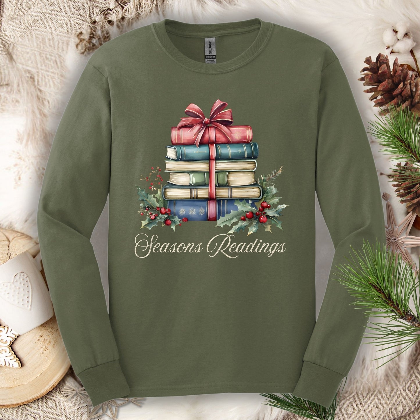 Military Green long sleeve tee with watercolor stack of vintage Christmas books, bow, holly, and "Seasons Readings" text.