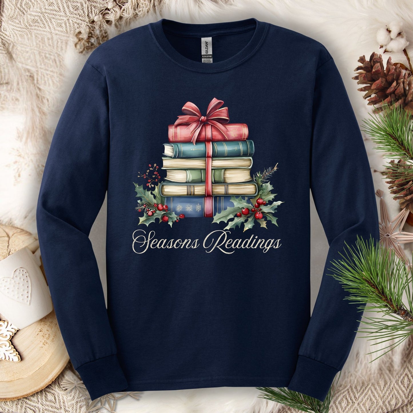 Navy long sleeve tee with watercolor stacked Christmas books, bow, holly, and "Seasons Readings" text.
