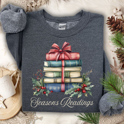 Dark heather unisex sweatshirt with a watercolor stack of vintage Christmas books, holly, and "Seasons Readings" text.