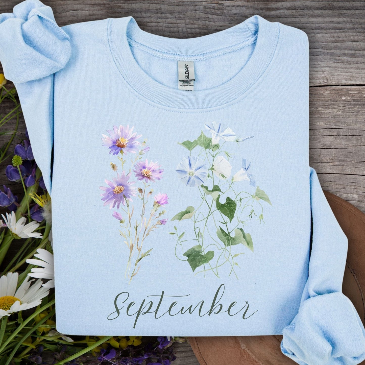 Light blue crewneck sweatshirt with watercolor morning glory and aster flowers, plus "September" text.