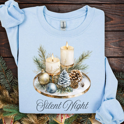Light blue Gildan sweatshirt with a watercolor "Silent Night" advent arrangement of candles, pinecones, and evergreens.