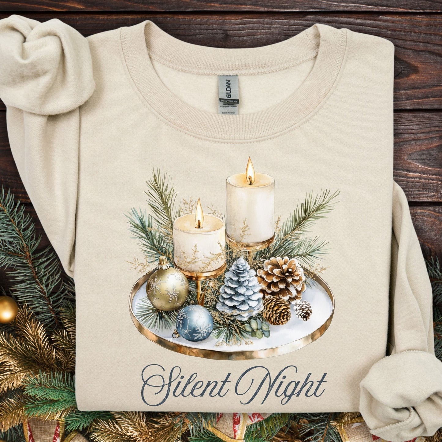 Sand Gildan sweatshirt with watercolor Silent Night advent arrangement: candles, pinecones, evergreens, blue/cream ornaments.