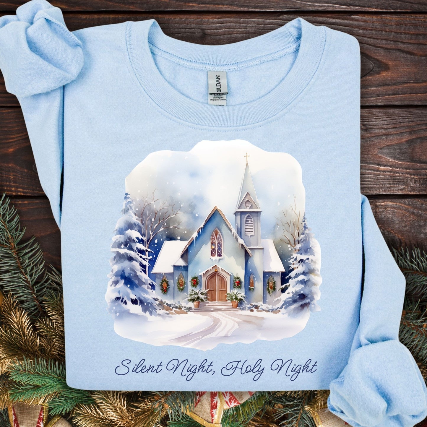Light blue Gildan fleece sweatshirt with a snowy country chapel design, evergreen garlands, and "Silent Night, Holy Night" text.