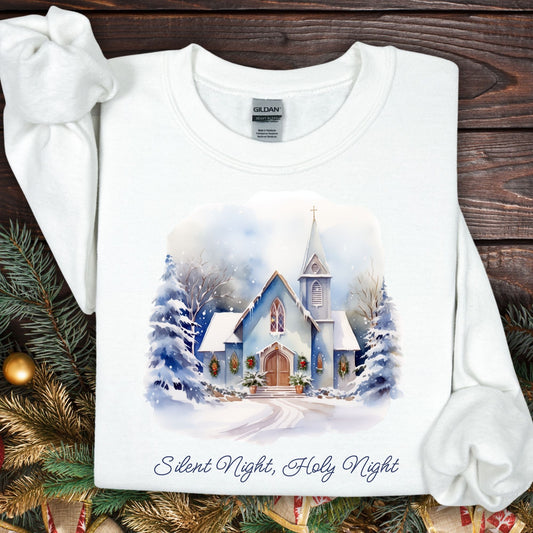 White Gildan fleece sweatshirt with a snowy country chapel design, evergreen garlands, and "Silent Night, Holy Night" text.
