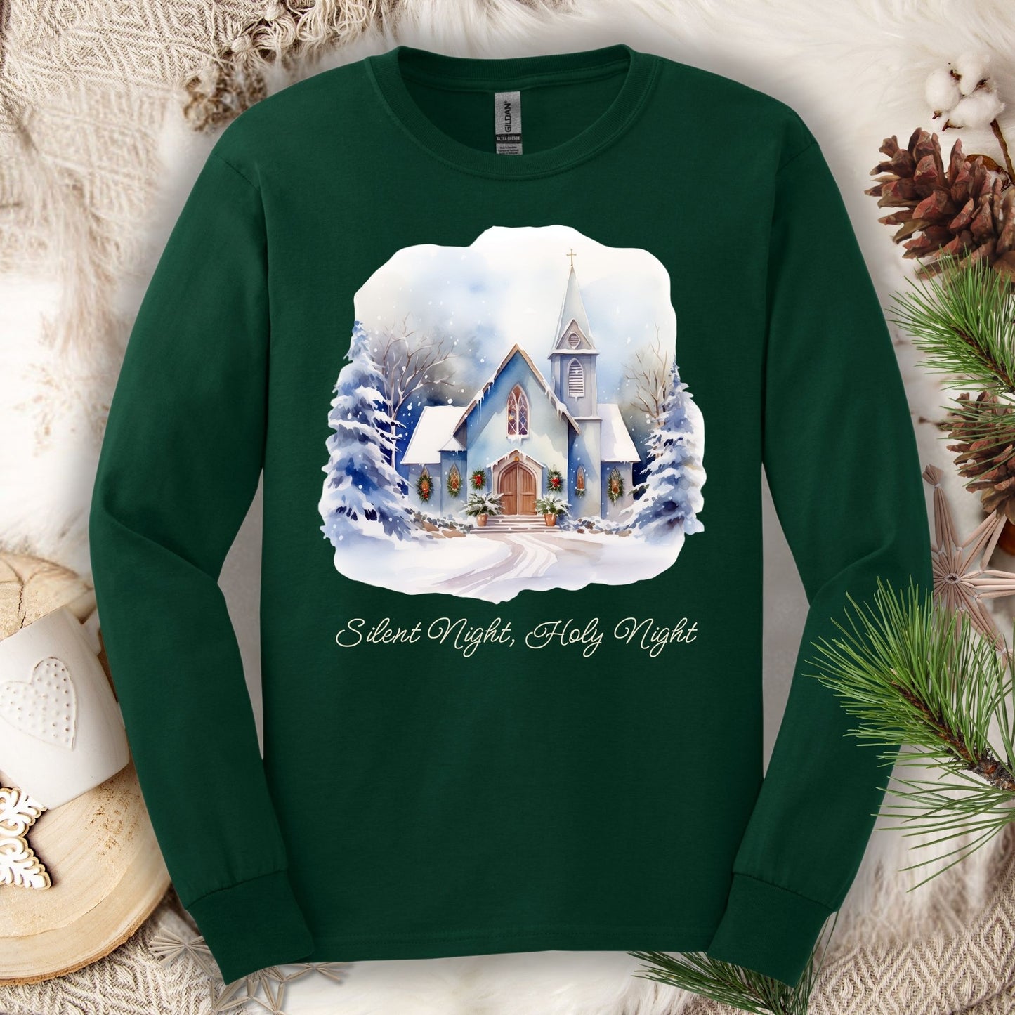 Forest Green long sleeve tee with watercolor snow-covered chapel, festive greenery, and "Silent Night, Holy Night" text.
