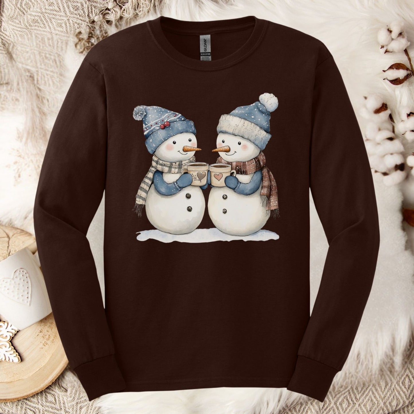 Dark Chocolate long sleeve tee with two snowpeople in blue hats and scarves holding hot chocolate.