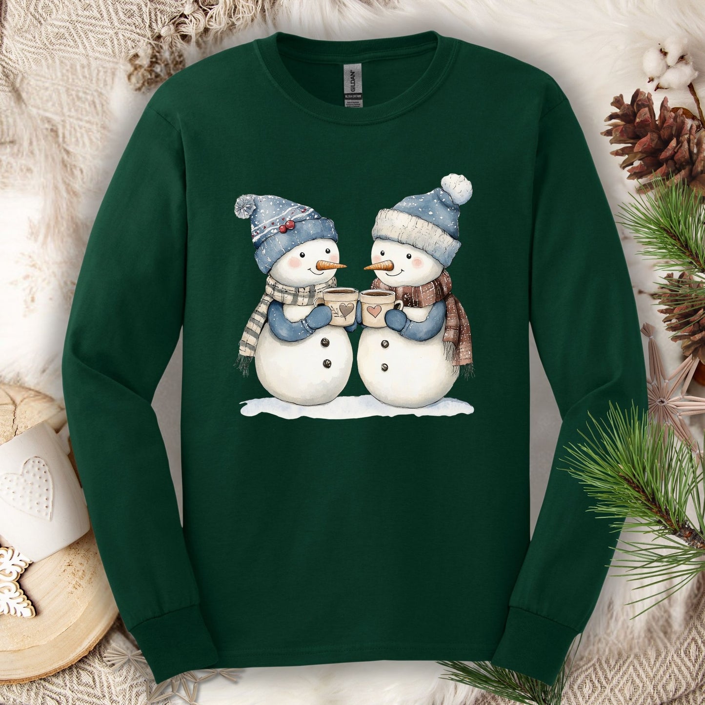 Forest Green long sleeve tee with two snowpeople in blue hats and scarves drinking hot chocolate.