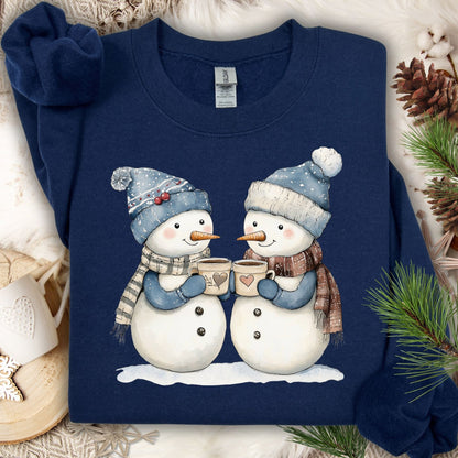 Navy S sweatshirt with two snowpeople in blue hats/mittens, holding hot chocolate, on a snowy backdrop.