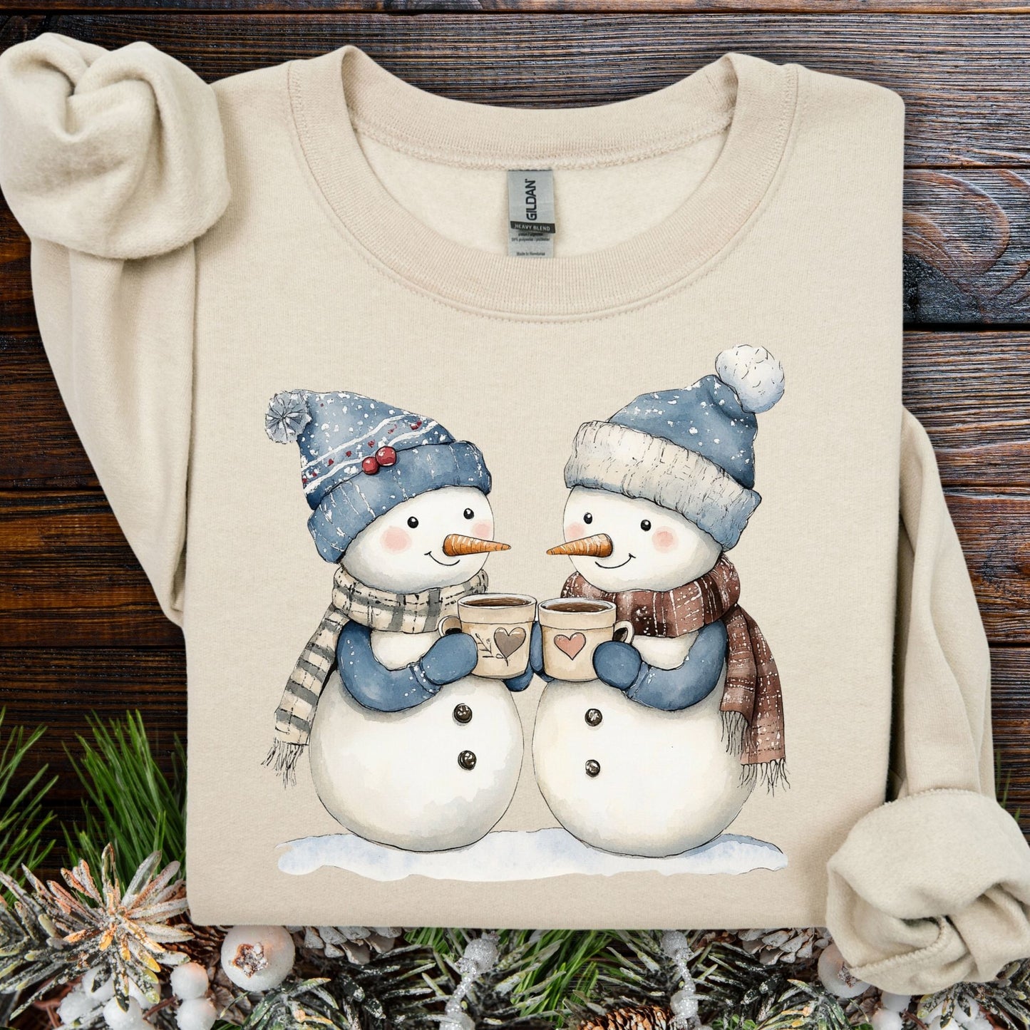 Sand S sweatshirt with two snowpeople in blue hats and scarves, holding hot chocolate.