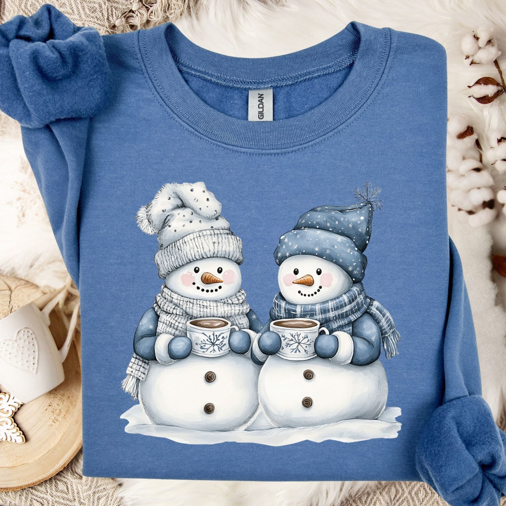 Indigo Blue heavy blend sweatshirt with two snowpeople in blue hats and scarves holding hot chocolate.