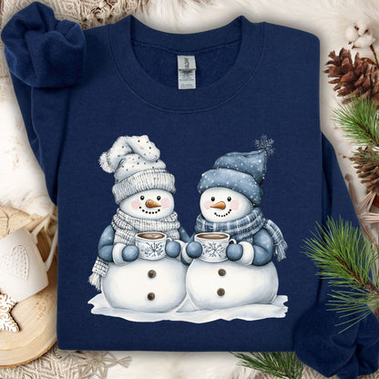 Navy heavy blend sweatshirt with two snowpeople in blue hats and scarves holding hot chocolate.