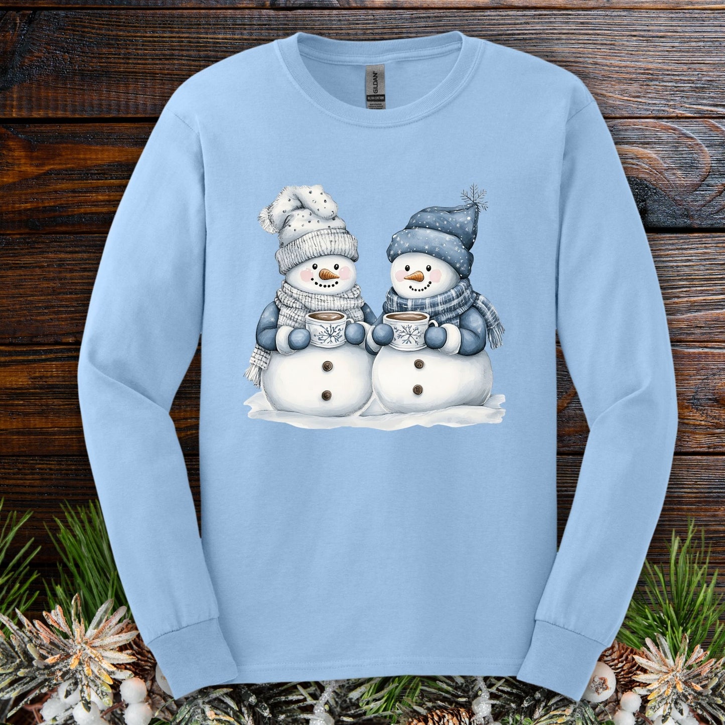 Light blue long-sleeve tee with two snowmen in hats and scarves holding hot chocolate mugs.