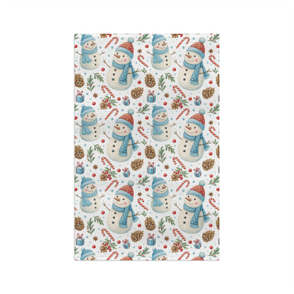 Holiday microfiber tea towel with a pattern of snowmen, candy canes, pine cones, and holly on white.