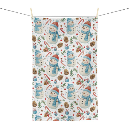 White microfiber tea towel with a repeating pattern of snowmen, candy canes, pine cones, and holly.