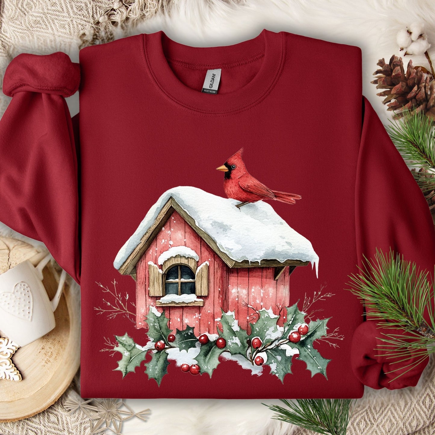 Cardinal Red Gildan sweatshirt with a watercolor cardinal on a snowy birdhouse, holly, and berries.