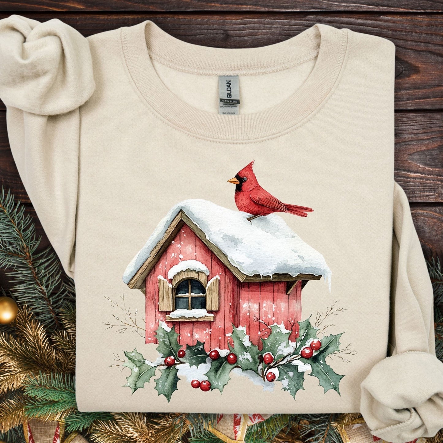 Sand Gildan fleece sweatshirt with a watercolor red cardinal on a snow-covered birdhouse and holly.