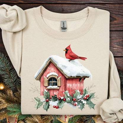 Sand Gildan fleece sweatshirt with a watercolor red cardinal on a snow-covered birdhouse and holly.
