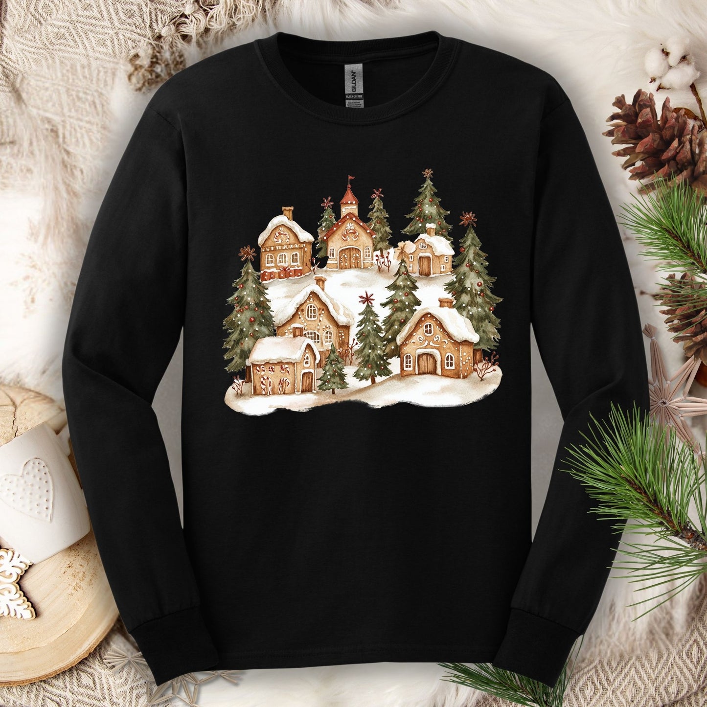 Black long sleeve tee with a watercolor snowy gingerbread village and evergreen trees design.