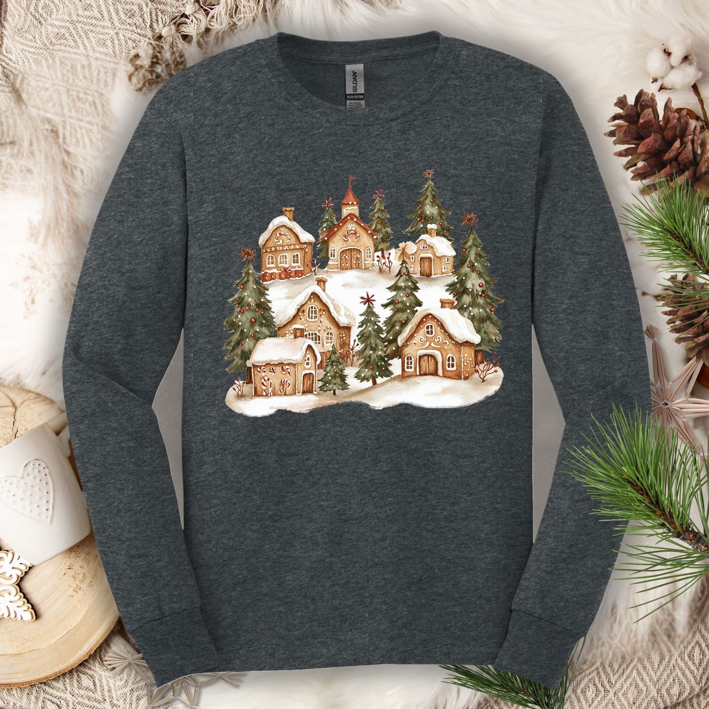 Dark heather long sleeve tee with a watercolor snowy gingerbread village and evergreens.
