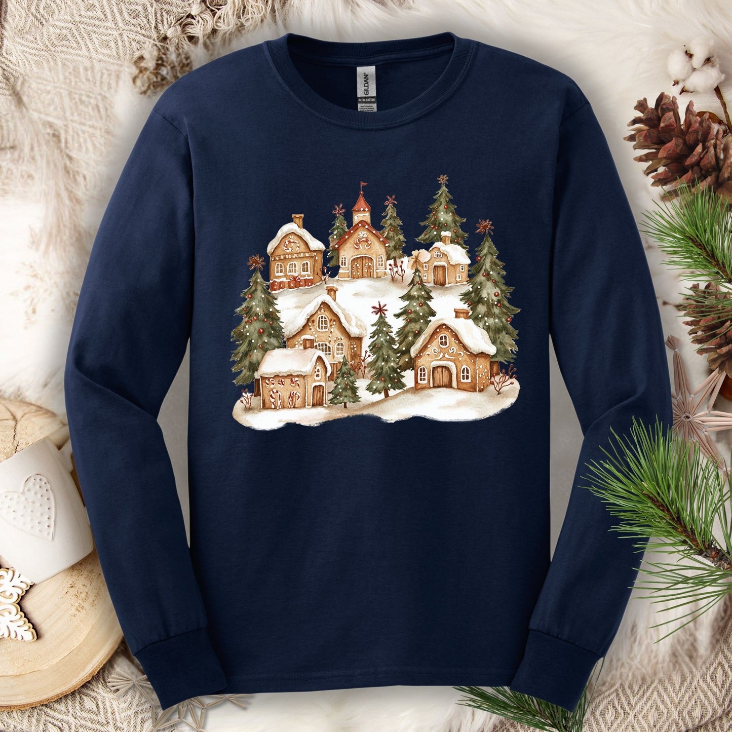 Navy long sleeve tee with a watercolor snowy gingerbread village and evergreens.